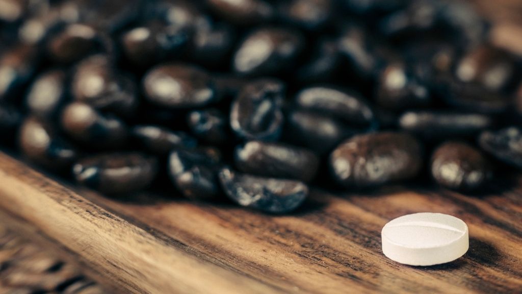 Vit tablett som ligger framför en hög med kaffebönor